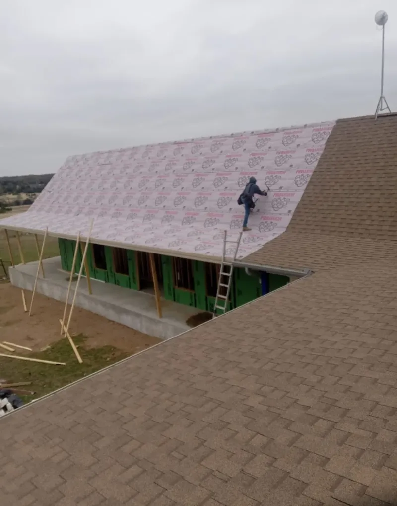 Worker preparing underlayment for a metal roof installation in Medfield